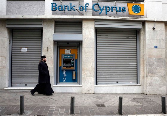 Pravoslavný mnich prochází kolem zavené poboky kyperské banky Bank of Cyprus