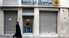 Pravoslavný mnich prochází kolem zavené poboky kyperské banky Bank of Cyprus