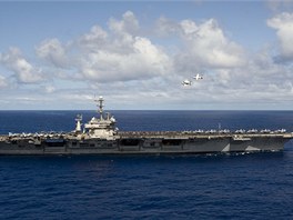 Posádka lodě mimo službu sleduje C-2A Greyhound (vpravo nahoře) a  E-2C Hawkeye...
