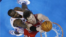 Omer Asik  z Houstonu smeuje, lepí se na nj Serge Ibaka z týmu Oklahoma City.