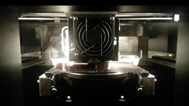 Samotný proces výroby hlavní. Uprostřed záběru je pohyblivá hlava tiskárny, která na sebe v určených místech klade vrstvy plastu. 
