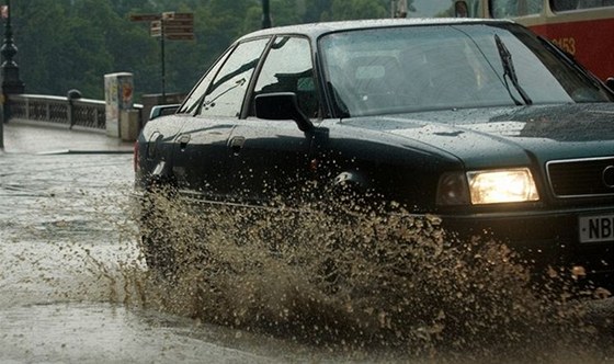 Auto projíždí mírně zatopenou silnicí.