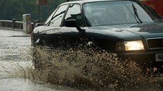 Auto projí�dí mírn� zatopenou silnicí.