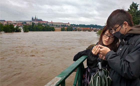 Zahraniní turisté sledují rozvodnnou Vltavu v Praze. (3. ervna 2013)
