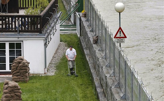 Muž seká trávník za protipovodňovou stěnou v dolnorakouském městečku