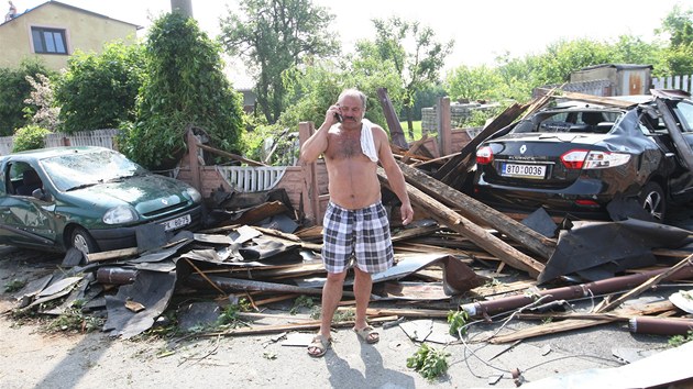 Josef Kobza u trosek stechy ze svho domu. Trmy zavalily i jeho auto (vlevo) a sousedv nov renault. (19. ervna 2013)