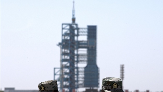 Čínští vojáci stojí před odpalovací rampou s kosmickou lodí Šen-čou-10 