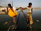 Dívky balancují na zatopených kolejích pi povodních v Thiaroye Sur Mer na
