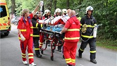 Záchranái s hasii peváejí tce zranného motorkáe od místa nehody k