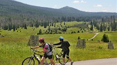 Cyklisté stoupají k hájence na Bezníku. Pod nimi se vine stezka Luzenským...