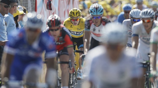 Chris Froome (ve lutm) dokonuje 13. etapu Tour de France v hlavnm pelotonu.