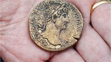 Archeolog ukazuje ímskou minci sestercius s portrétem císae Hadriana. Byla