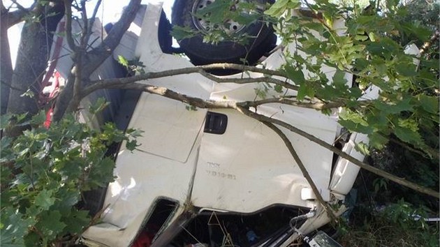 Kamion prorazil svodidla a skutlel se ze srzu. idi kamionu zstal uvznn v kabin a zranil se i ofr osobnho auta. (10. srpna 2013)