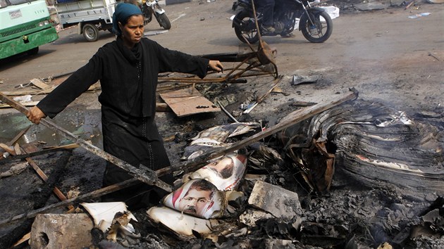 Egypťanka prohledává spáleniště na káhirském náměstí Nahda. Na zemi jsou ohořelé plakáty s podobiznou svrženého prezidenta Mursího (15. srpna 2013).