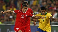 Švýcarský fotbalista Granit Xhaka (vlevo) v souboji s Brazilcem Hulkem.