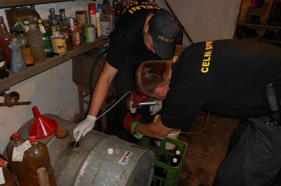 Celníci odebírají vzorky z nalezeného alkoholu.