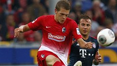 Oliver Sorg (vlevo) z Freiburgu odehrává míč před Mariem Götzem z Bayernu...
