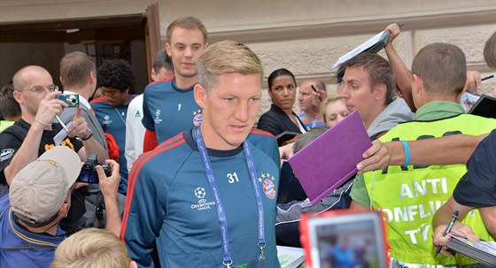 Bastian Schweinsteiger (v popedí) a Manuel Neuer se prodírají zástupy fanouk...