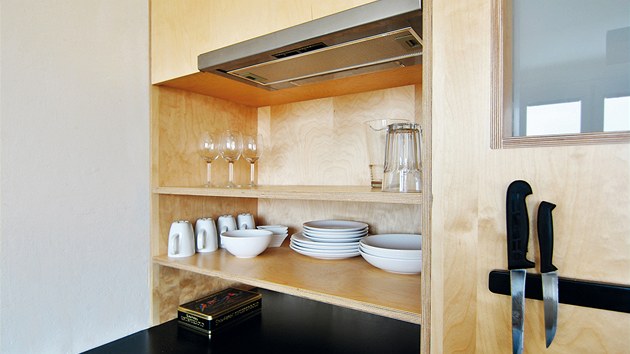 Kuchyňská sestava je řešena účelně bez nástěnných skříněk, takže vynikne její zadní stěna z překližky. 