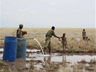 Keňský policista podává vodu žíznivému dítěti u vrtu v Lotikipi. (Keňa, září
