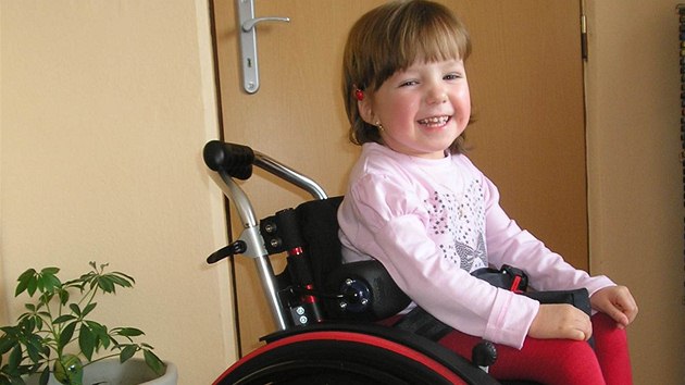Janička se svým novým mechanickým vozíkem, který jí pomáhá v každodenním životě. Náklady na jeho koupi byly vysoké, proto Nadace Naše dítě dívce pomohla.