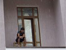 A migrant worker sits on a balcony in the village of Krasnaya Polyana, a venue...