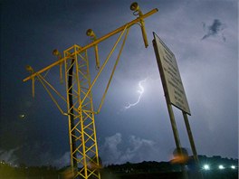 A lightning flashes in the sky above the Alder airport as people pass by a...