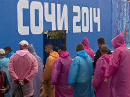 Builders stand in a line to enter a canteen in the Olympic Park in the Adler...
