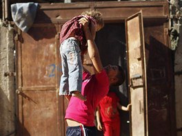 Newly married Ahmed Soboh, 15, plays with his brother (top) outside their house...