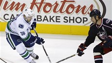 Jannik Hansen (v bílém) z Vancouveru proniká kolem Boona Jennera (38) a...