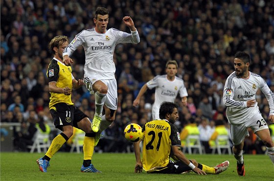 Gareth Bale utíká obran FC Sevilla, vpravo jeho snahu sleduje spoluhrá z