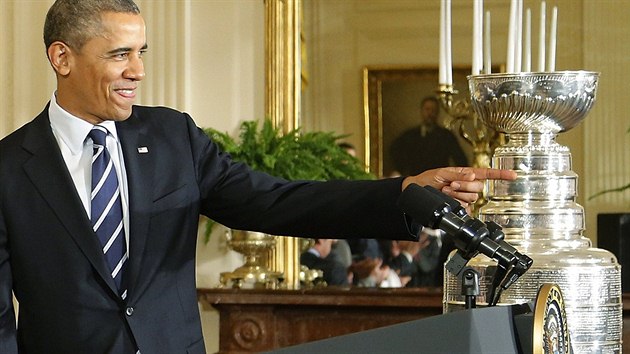 Americk prezident Barrack Obama stoj ped einckm pultkem, za nm se blsk slavn Stanley Cup.