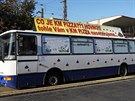 Kloubový autobus s vulgárními nápisy a figurou oběšence (leží za bannerem),...