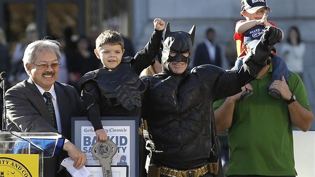 Ptilet Miles Scott v obleku malho Batmana pzuje po zvod ped radnic, vlevo je starosta Ed Lee, zcela vpravo Scottv tatnek s bratkem na ramenou.