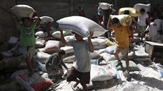 Peiví obyvatelé Filipín odnáejí pytle s rýí ze znieného skladit. 