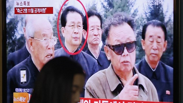 ena v jihokorejskm Soulu prochz kolem obrazovky s archivnm snmkem, na kterm je popraven ang Song-tchek (v krouku) a bval vdce KLDR Kim ong-il. (13. prosince 2013)