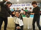 Student v masce Kim ong-una dává palec dol studentovi s maskou vdcova strýce...