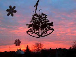 Pohled na mrazivé svítání přes vánočně nazdobené okno ve Skuhrově na...