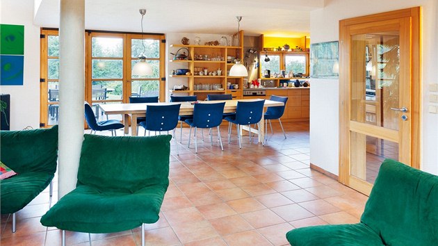 Obývací pokoj otevřený do krovu je propojený s kuchyní. Z vložené galerie jsou přístupné ložnice v patře. Zelená křesla potažená umělou kůží alcantara jsou francouzské značky Ligne Roset. 


