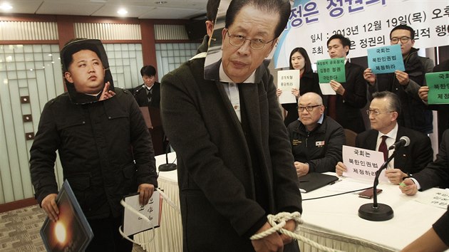 Dozorce vede ang Song-tcheka, kter byl obvinn z pokusu o pevrat a popraven, za nm kr severokorejsk vdce Kim ong-un. Masky si nasadili jihokorejt studenti v Soulu.