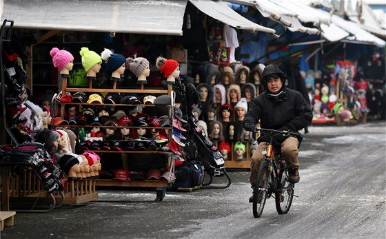 Trhovec pejídí na kole po zledovatlé cest mezi stánky v nejvtím