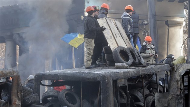 My se nedme! Demonstranti vyzbrojen dlnickmi helmami vartuj na ohoelm autobuse v centru Kyjeva (27. ledna 2013)