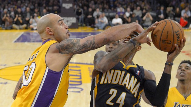 Paul George z Indiany se sna udret m, napad ho  Robert Sacre z LA Lakers.