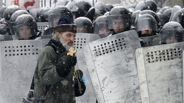 Pravoslavn knz prochz kolem policejnho kordonu ve stedu Kyjeva. (22. ledna 2014)