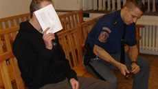 Ob�alovaný Michal �erný si p�ed noviná�i zakrýval obli�ej.