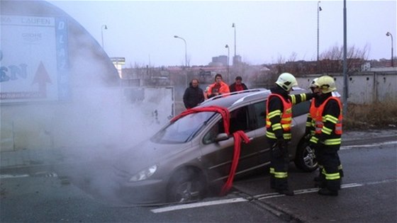 Brnntí hasii vyproují auto, které v nedli vjelo do propadnuté díry ve