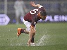Francesco Totti z AS ím padá na podmáený trávník Olympijského stadionu.