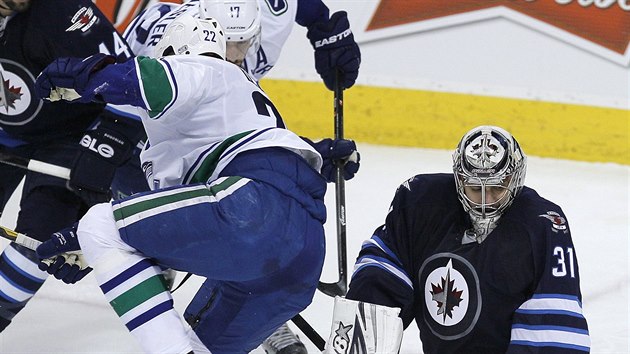 Ondej Pavelec v brance Winnipegu zasahuje ped vancouverskm Danielem Sedinem.