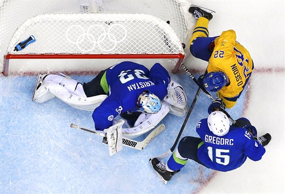 védský hokejista Daniel Sedin se snaí dorazit puk za záda slovinského gólmana