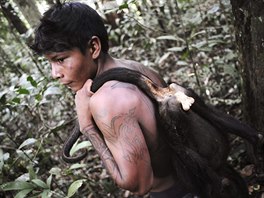 A Munduruku Indian warrior carries a monkey he hunted for food during a search...